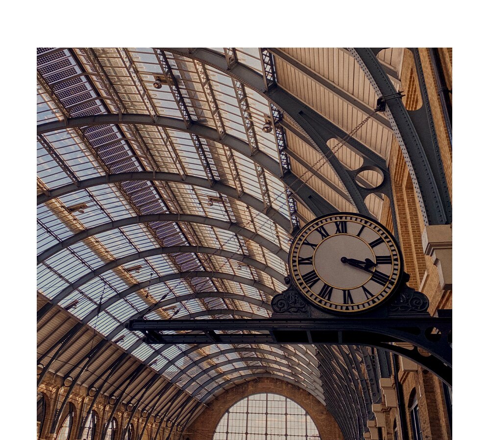Railway station clock with glass roof in the background
